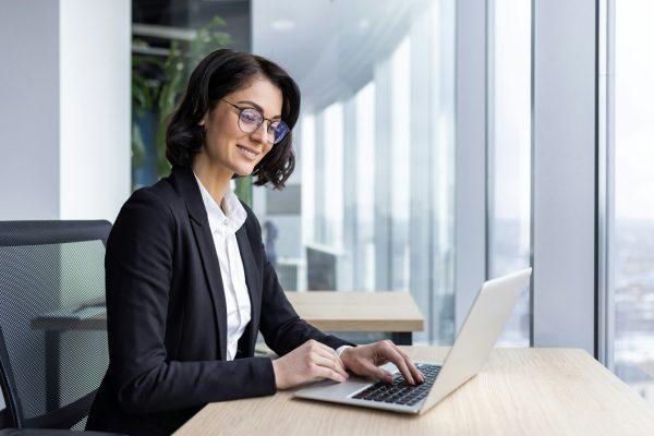 Businesswoman mature boss at workplace inside office, woman in business suit working contentedly