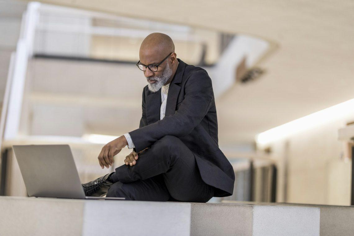 Bald mature businessman looking at laptop thinking