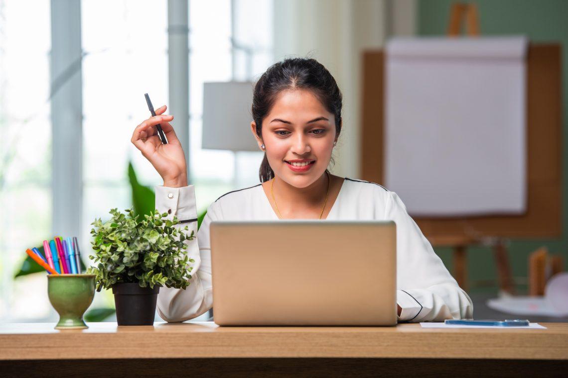 Indian asian young beautiful female business woman working on laptop on table or desk